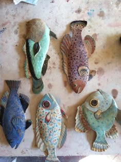 five ceramic fish sitting on top of a table next to each other in different colors