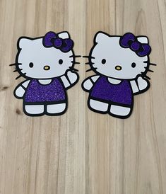 two hello kitty stickers sitting on top of a wooden table