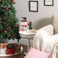 a small christmas tree in the corner of a living room with presents on the table