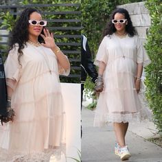 two women in dresses and sunglasses walking down the street with one holding her hand up to her face