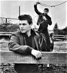 black and white photograph of two men riding horses with one man on horseback holding an object in the air