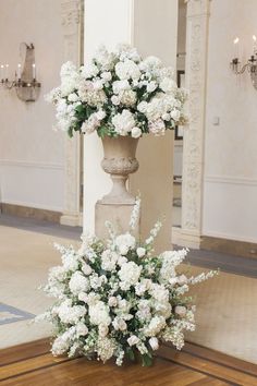 two tall vases with white flowers are on the floor