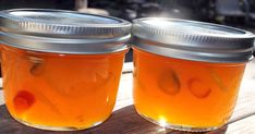 two jars filled with liquid sitting on top of a wooden table