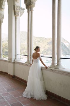 a woman in a wedding dress leaning against a wall