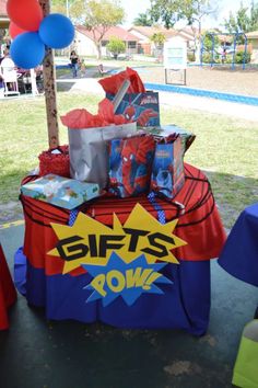 a table with gifts and balloons on it at a birthday party in the park or playground