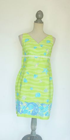 "This darling Lilly Pulitzer Maternity dress is perfect for summer.  It is sleeveless with an empire waist. The print is called \"low tide\" and features a wavy pattern of light and bright green with aqua and peach shells, with a five inch border of dark periwinkle crabs and fish and aqua and peach colored shells near the hem. There is a strip of white open cut lace at the empire waist. The dress is fully lined and made of 97% cotton with 3% spandex so it has a little stretch to it. The back has a 21 inch zipper and a 3 inch slit at the hem. Size Medium. *See measurements.    -Measurements:     -Bust: 36-37 inches     -Hips: 40 inches     -Length: 34 inches(measured from back of neck to hem) --------------------------------------------------------------------------------------------------- Fitted Lined Sleeveless Dress For The Beach, Beach Sundress With Lining, Beach Sundress Sleeveless And Lined, Lined Sleeveless Sundress For Beach, Green Lined Sleeveless Summer Dress, Green Lined Sleeveless Dress For Summer, Fitted A-line Sleeveless Beach Dress, Knee-length Lined Sundress For Vacation, Lined Knee-length Sundress For Vacation