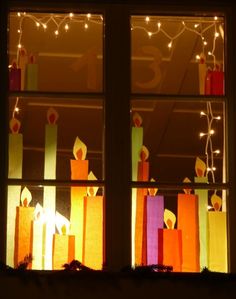 brightly colored candles are lit in front of a window