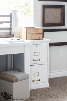 a white desk with two drawers and a plant in the window sill next to it