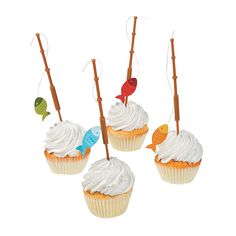 four cupcakes with white frosting and fish decorations on sticks in front of them