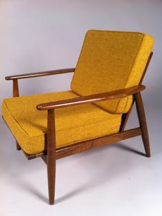 a yellow chair sitting on top of a white floor next to a wooden arm rest