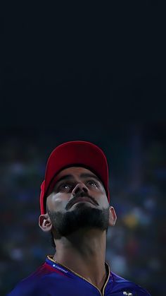 a man with a beard wearing a red hat looking up at something in the sky