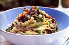 a blue bowl filled with pasta and vegetables