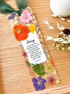 a bookmark with flowers on it sitting next to some dried grass and an egg