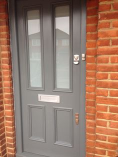 the front door is painted gray and has two glass panels on each side, along with a brick wall