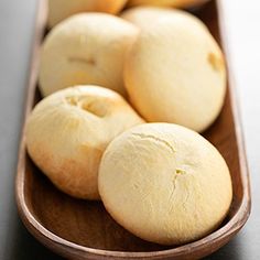 a wooden bowl filled with doughnuts on top of a table