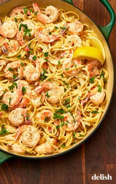 a pan filled with shrimp and pasta on top of a wooden table