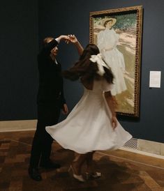 a man and woman standing in front of a painting