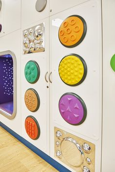 a child's play area with different shapes and sizes on the wall, including buttons