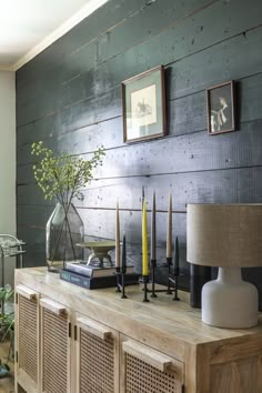 a table with candles, vases and pictures on the wall behind it in a living room