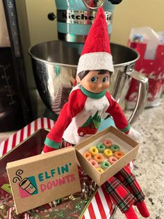 an elf is holding a box of doughnuts