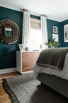 a bedroom with teal walls and wood flooring is pictured in this image, there are pictures on the wall above the bed