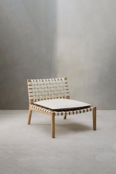 a white chair sitting on top of a floor next to a gray wall and wooden frame