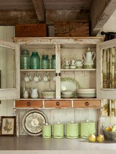 an old fashioned kitchen with lots of cupboards and dishes on the counter top in front of it