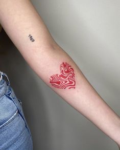 a woman's arm with a red and white tattoo design on the left forearm