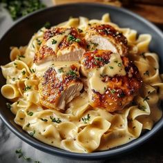 a black bowl filled with pasta and meat covered in sauce