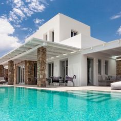 a house with a swimming pool in front of it and lounge chairs around the pool