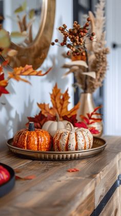 a wooden table topped with pumpkins and other autumn decorations