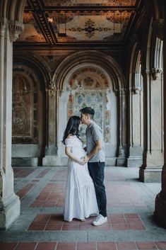 a man and woman are kissing in an old building with arches on either side of them