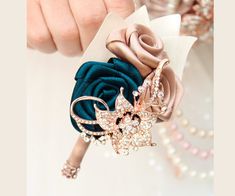 a close up of a person's hand holding a flower brooch