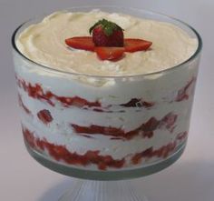 a cake with strawberries on top is in a glass dish, ready to be eaten