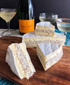 several pieces of cheese sitting on top of a wooden cutting board next to wine glasses