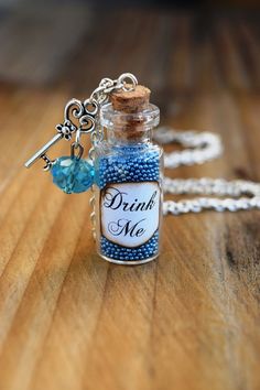 a bottle filled with blue beads sitting on top of a wooden table next to a chain