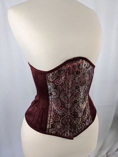 Burgundy Silver and Gold Brocade and Satin Steel Boned Low Curve Mid Hip Underbust Corset This listing is for a made to order corset made using our custom pattern! Constructed from a stunning Burgundy, Silver, and Gold Brocade paired with a beautiful Burgundy Satin with a cotton twill liner, this corset is perfect for victorians and goths alike.  This corset is made of a Burgundy, Silver and Gold Brocade and Burgundy satin, tied together with Burgundy binding, burgundy stitching, burgundy laces, Victorian Fitted Underbust Corset, Elegant Underbust Bodice For Costume, Elegant Red Underbust Corset, Elegant Red Corset With Boned Bodice, Victorian Overbust Fitted Corset, Victorian Fitted Corset For Costume, Elegant Boned Corset For Costume, Elegant Boning Corset For Costume, Elegant Costume Corset With Boning