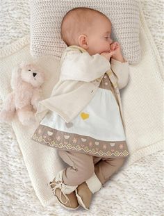 a baby laying on top of a blanket next to a teddy bear