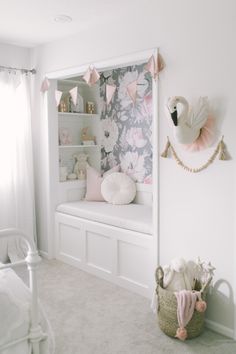 a baby's room with white walls and pink accessories on the shelves, along with a floral wallpaper