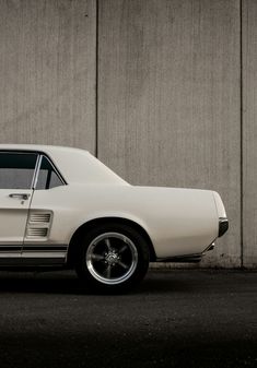 an old white car parked in front of a building with no doors on it's side