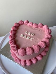 a heart shaped cake with the words leo baby on it's frosting and pink icing