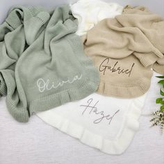 four different colored sweaters with writing on them and some flowers in the corner next to it