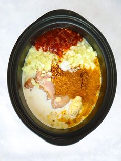 ingredients in a black bowl on a white table top, including spices and seasonings