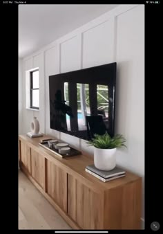 a large flat screen tv mounted to the side of a wooden cabinet in a living room