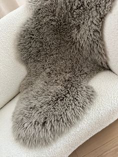 a grey furry animal rug sitting on top of a white couch