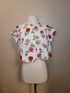 This is a very hard to find beach surfer top in the style of the TV Star Gidget or Annette Funicello. Great with a pair of Capri pants or pedal pushers.Original buttons are in tact, no tears. Please see photos for barely noticeable staining. Size XS/S Measurements: Length: 16.5" Shoulders: 14" Waist/Hips: Free Bust: 32" Disclaimer: All items from this store are authentic vintage and come from a pet free/smoke-free environment. Colors may be different on each digital screen. All notable damage is listed, but if you have noticed something small, please contact me as it was truly an oversight. All sizing is approximate. Please reach out for any further questions regarding sizes or damage before purchasing. But as this is vintage (and that's why we love it!) unless this item is grossly misrepr Tropical Crew Neck Tops For Spring, Stretch Floral Print Top For Beach Season, Summer Stretch Tops With Tropical Print, Stretch Tropical Print Summer Tops, Stretch Cotton Beachwear Top, Fun Summer Tops With Floral Print, Stretch Tropical Print Top For Summer, Summer Tropical Print Stretch Tops, Fun Floral Print Tops For Summer