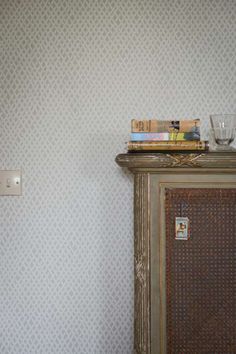 a bookshelf with some books on top of it next to a wall paper