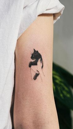 a black and white cat tattoo on the arm