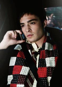 a young man in a tie is talking on his cell phone while wearing a scarf