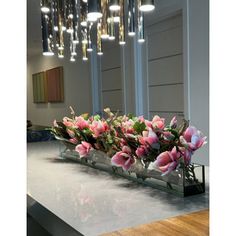 a vase filled with pink flowers sitting on top of a counter next to a mirror